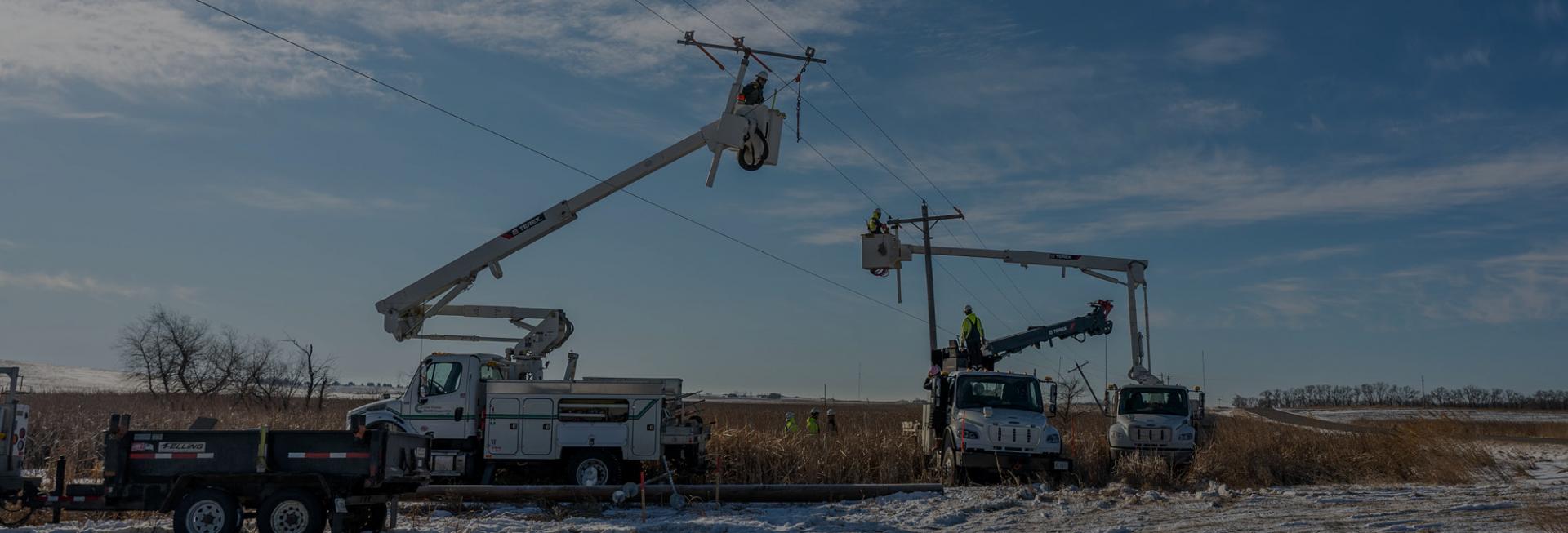 Picture of bucket trucks and lineworkers working to restore power