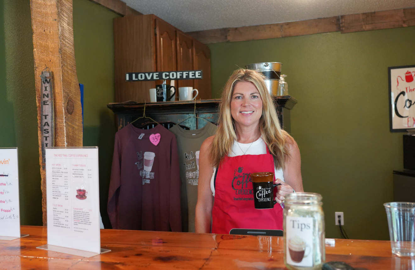 Employee of the Red Trail Vineyard coffee shop holding a mug